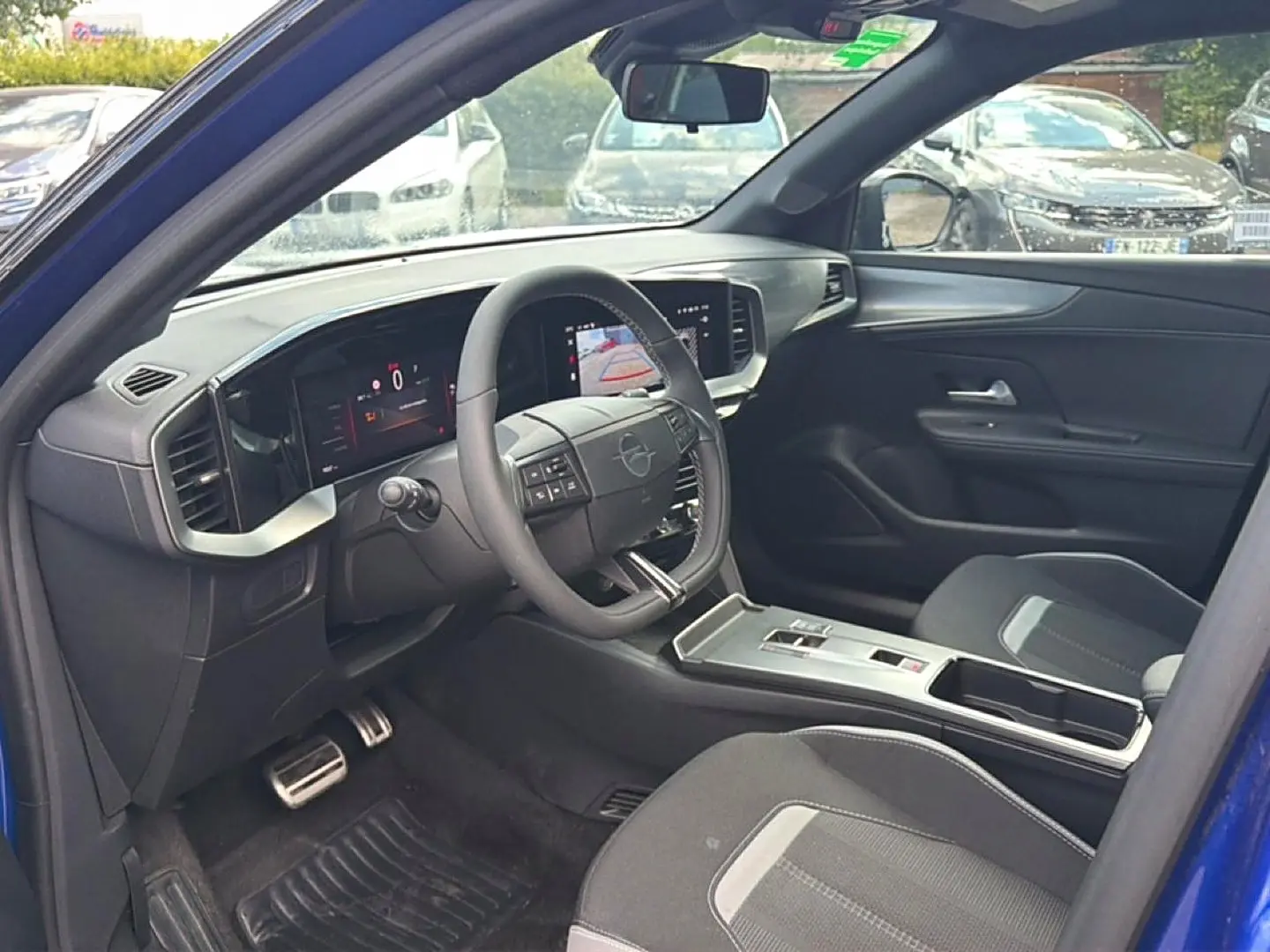 Vue intérieure côté conducteur de l'Opel Mokka Electric 156 gs bleu, avec tableau de bord numérique et volant multifonction.