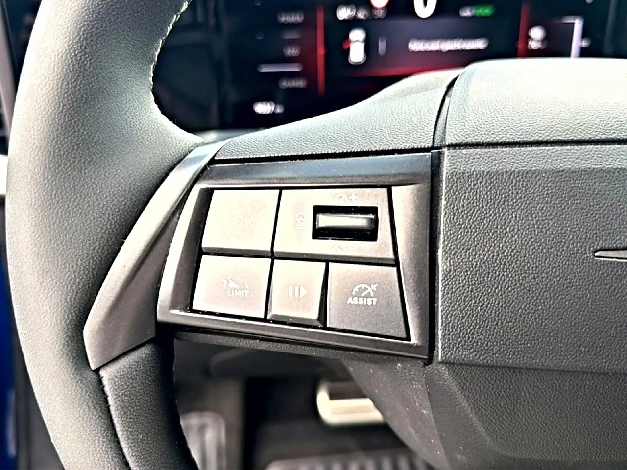Gros plan sur les commandes gauche du volant noir de l'Opel Mokka Electric 156 gs, avec boutons multifonctions visibles.