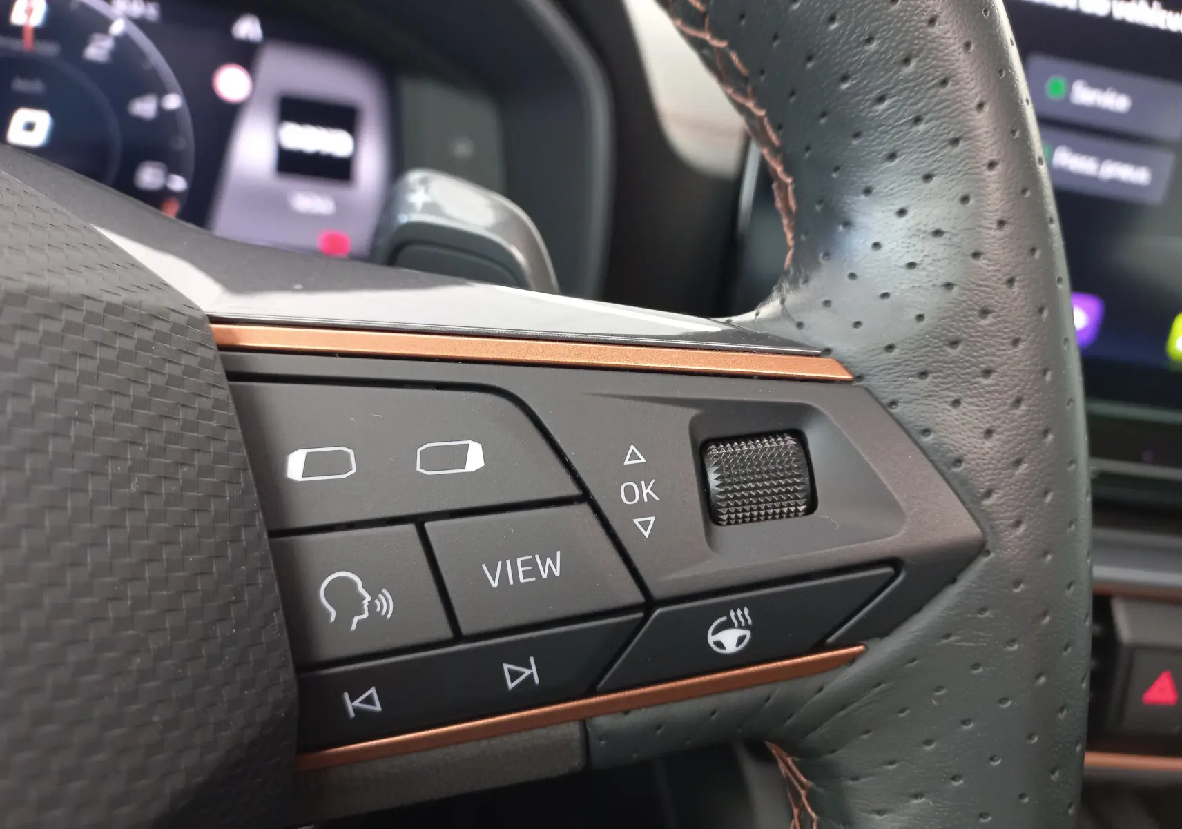 Gros plan sur les commandes du volant en cuir perforé noir du CUPRA Formentor 1.4 e-HYBRID 2024 avec insert cuivre.