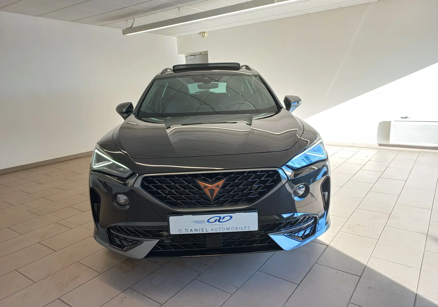 Vue avant d’un CUPRA Formentor noir minuit avec calandre marquée et phares Matrix LED allumés, en intérieur lumineux.