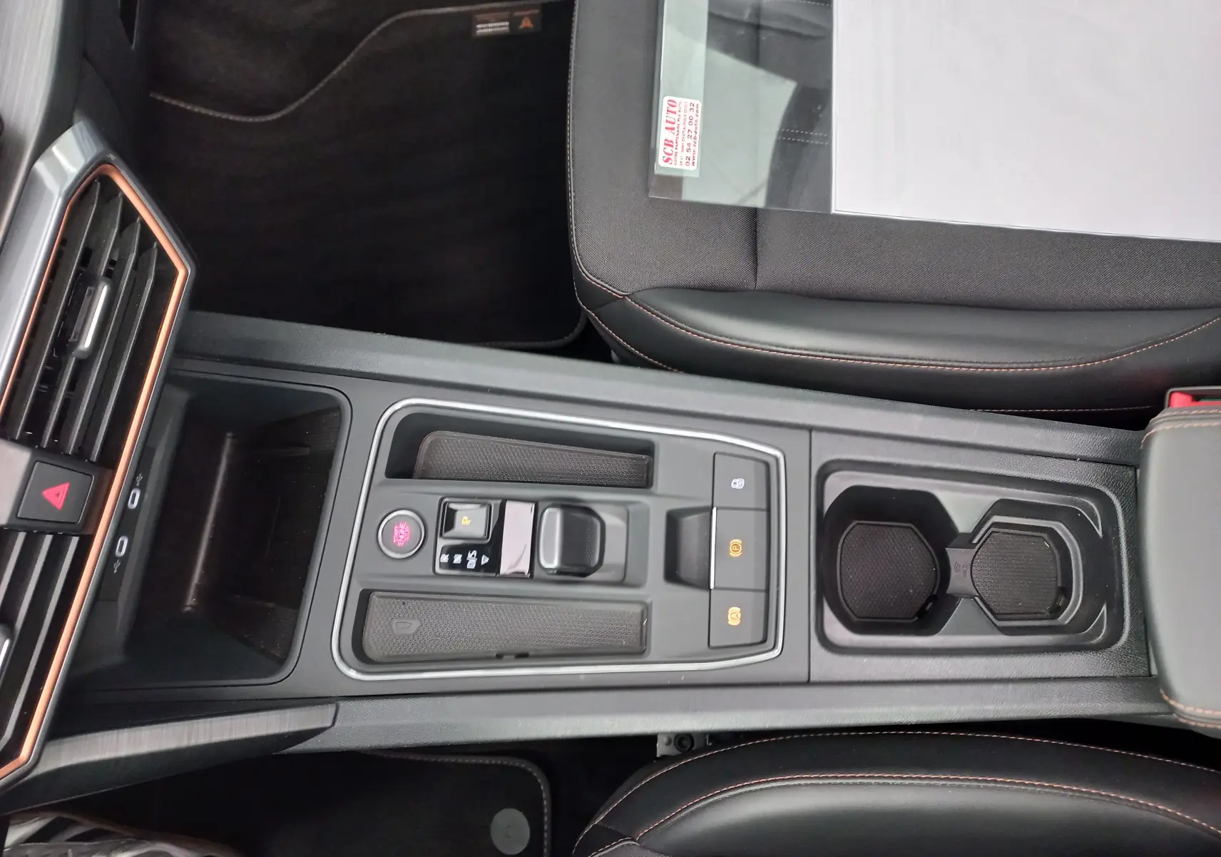 Vue plongeante sur la console centrale noire du CUPRA Formentor 2024 avec surpiqûres orange et commandes électroniques.