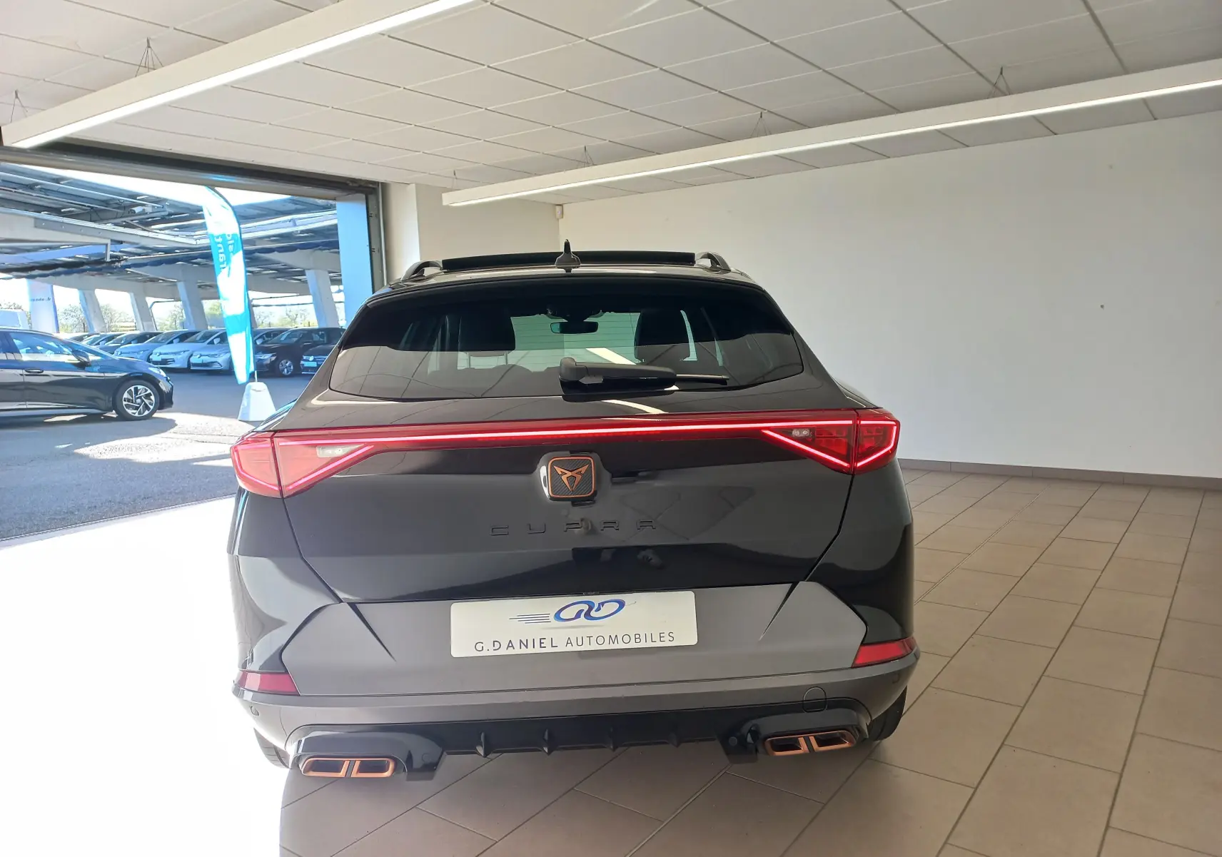 Vue arrière d'un CUPRA Formentor noir minuit avec feux LED en bandeau et double sortie d'échappement cuivrée.