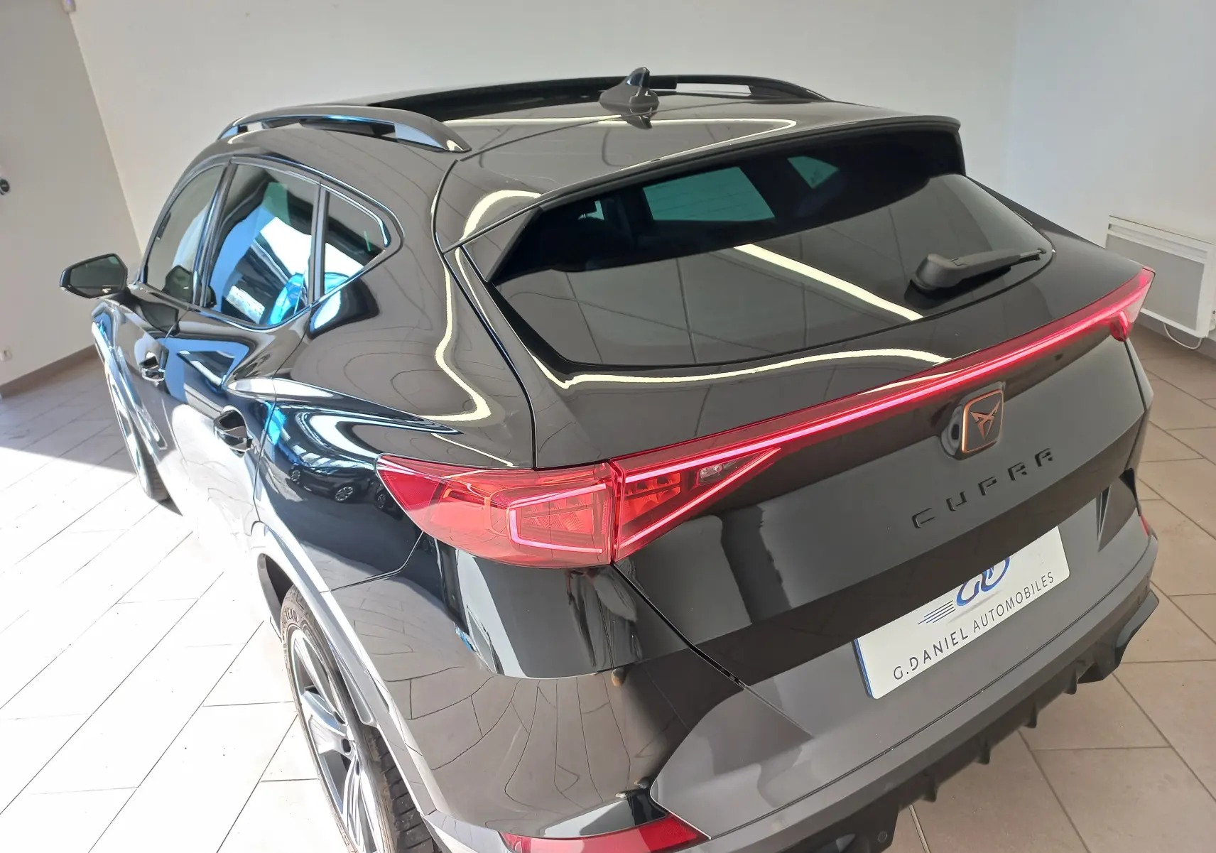 Vue 3/4 arrière droite du CUPRA Formentor noir minuit, soulignant la ligne dynamique et le feu arrière continu LED.