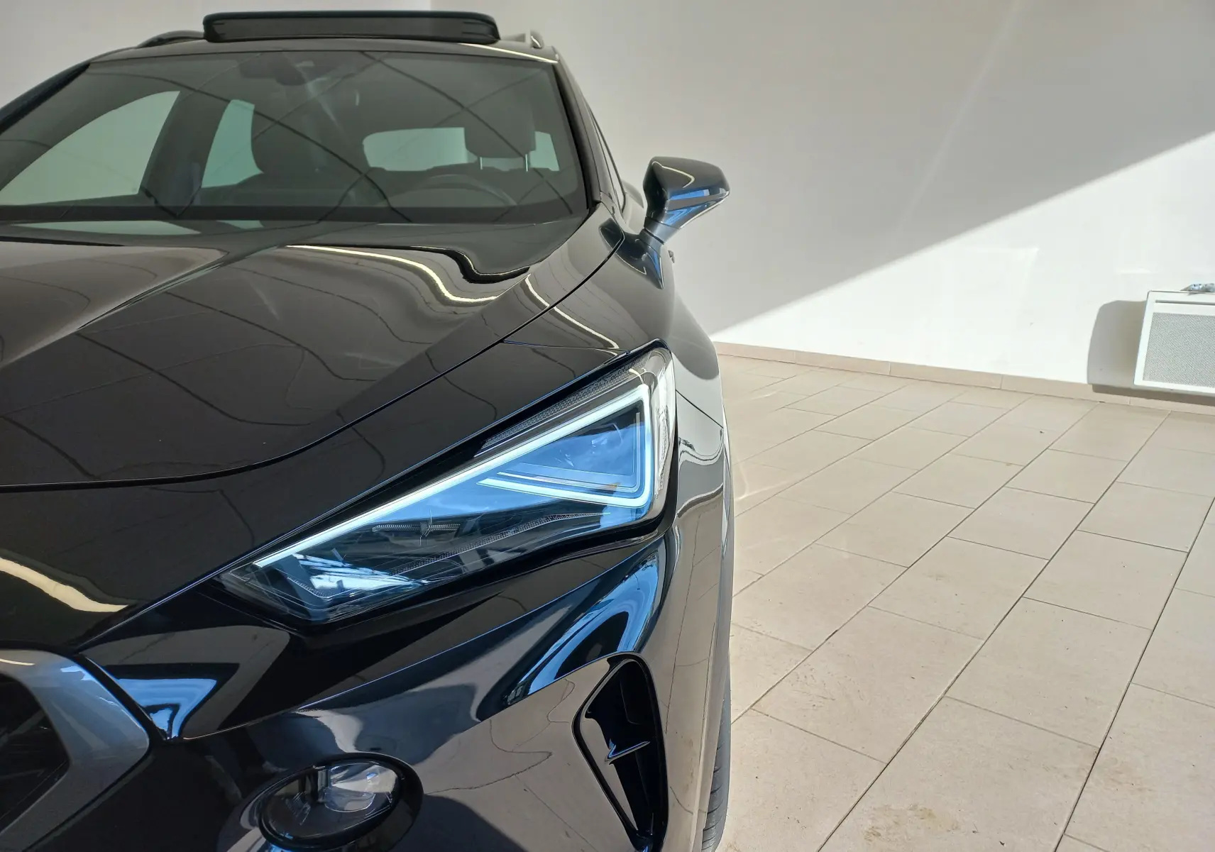 Gros plan sur l'avant droit noir minuit du CUPRA Formentor 1.4 e-HYBRID 204 ch avec projecteur Matrix LED distinctif.