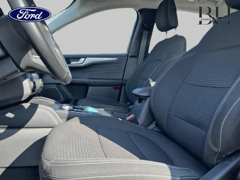Vue intérieure côté conducteur du Ford Kuga 2022 avec sièges sport noirs et accoudoir central.