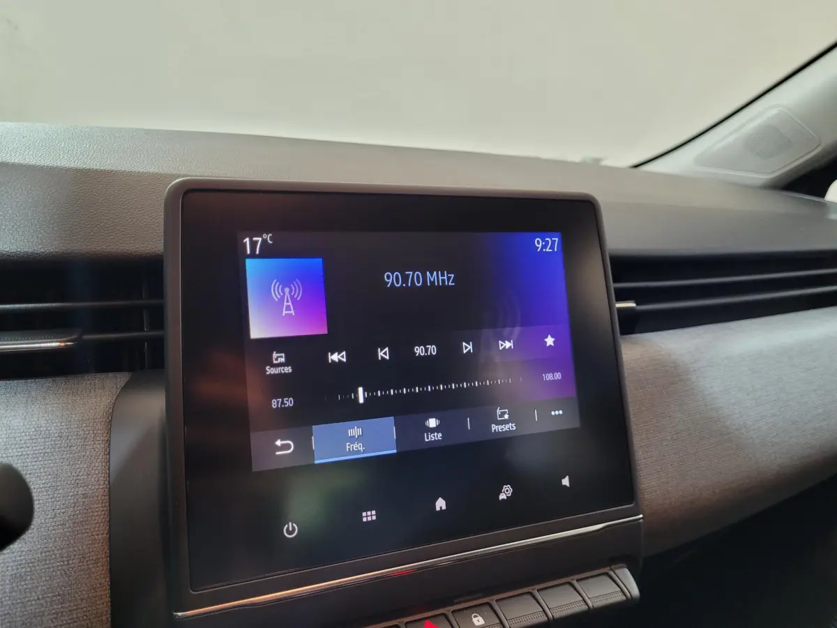 Écran tactile central de la Renault Clio gris foncé affichant la radio FM à 90,70 MHz dans l'habitacle.