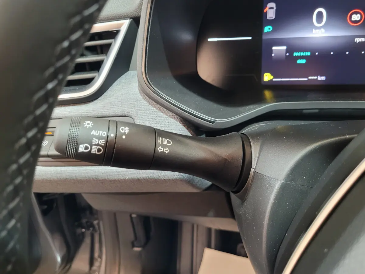 Gros plan sur la manette des feux et clignotants à gauche du volant dans le tableau de bord gris foncé de la Renault Clio 2025.