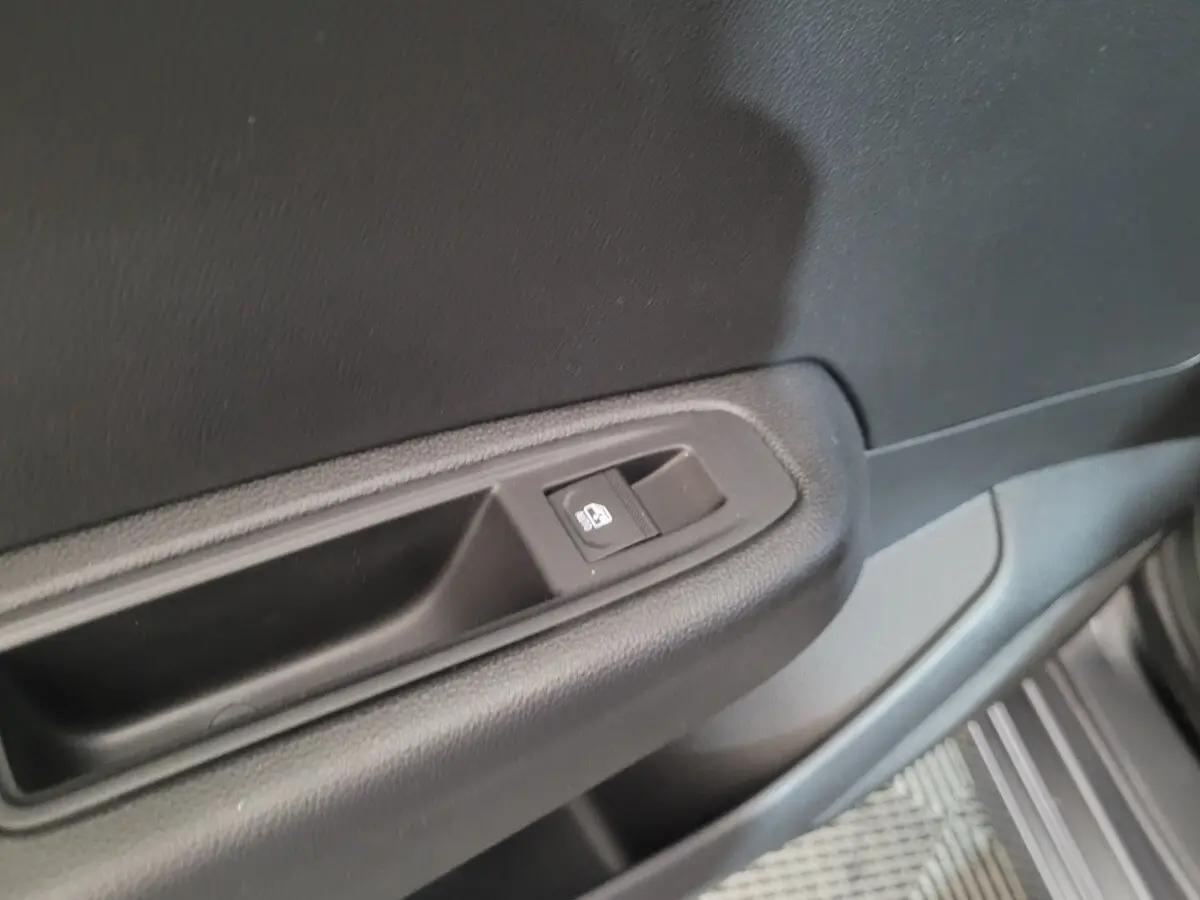 Bouton de commande de vitre sur la porte côté conducteur d'une Renault Clio gris foncé, intérieur sobre en plastique noir.