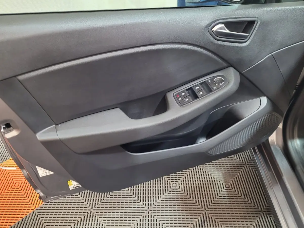 Porte intérieure côté conducteur de Renault Clio gris foncé, avec commandes électriques des vitres et poignée intégrée.