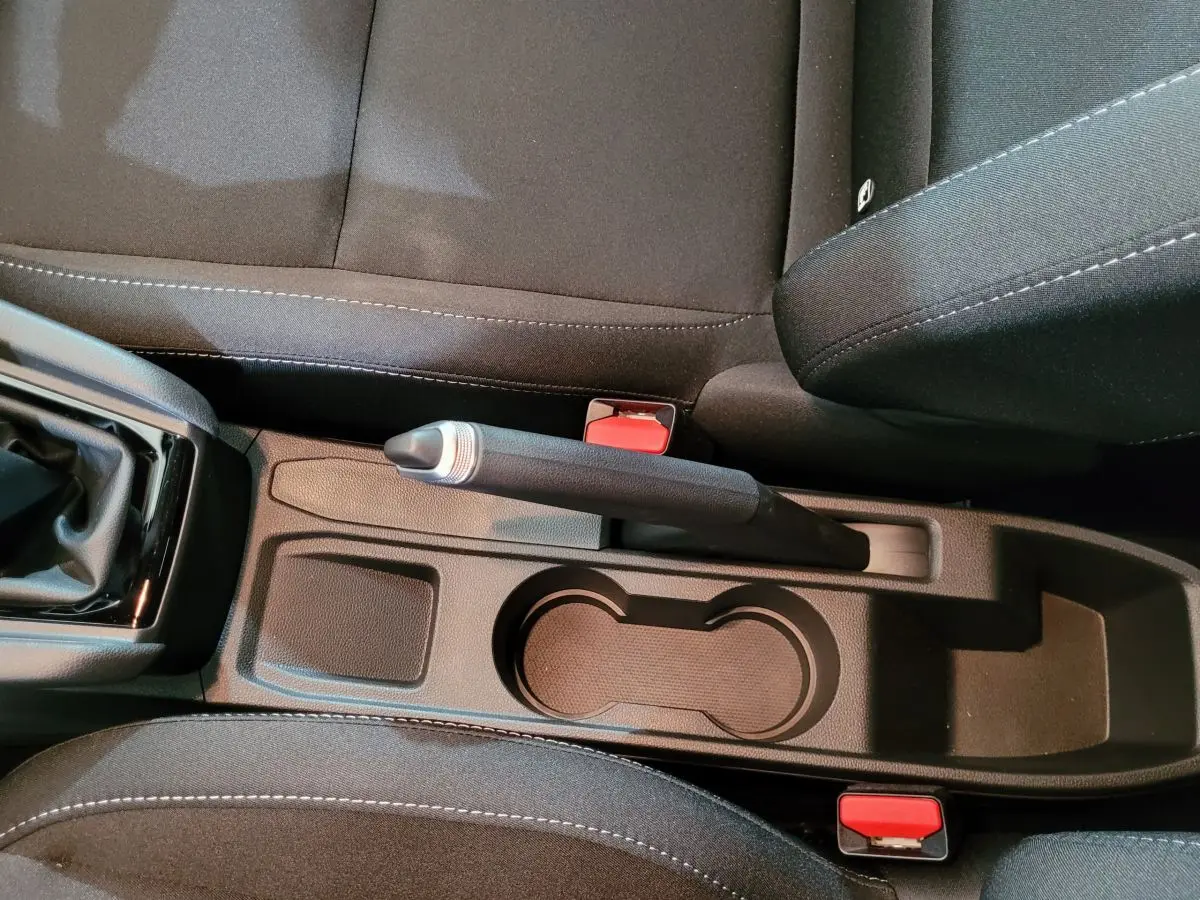 Vue rapprochée de la console centrale noire avec frein à main manuel et porte-gobelets de la Renault Clio gris foncé Evolution Blue dCi 100.