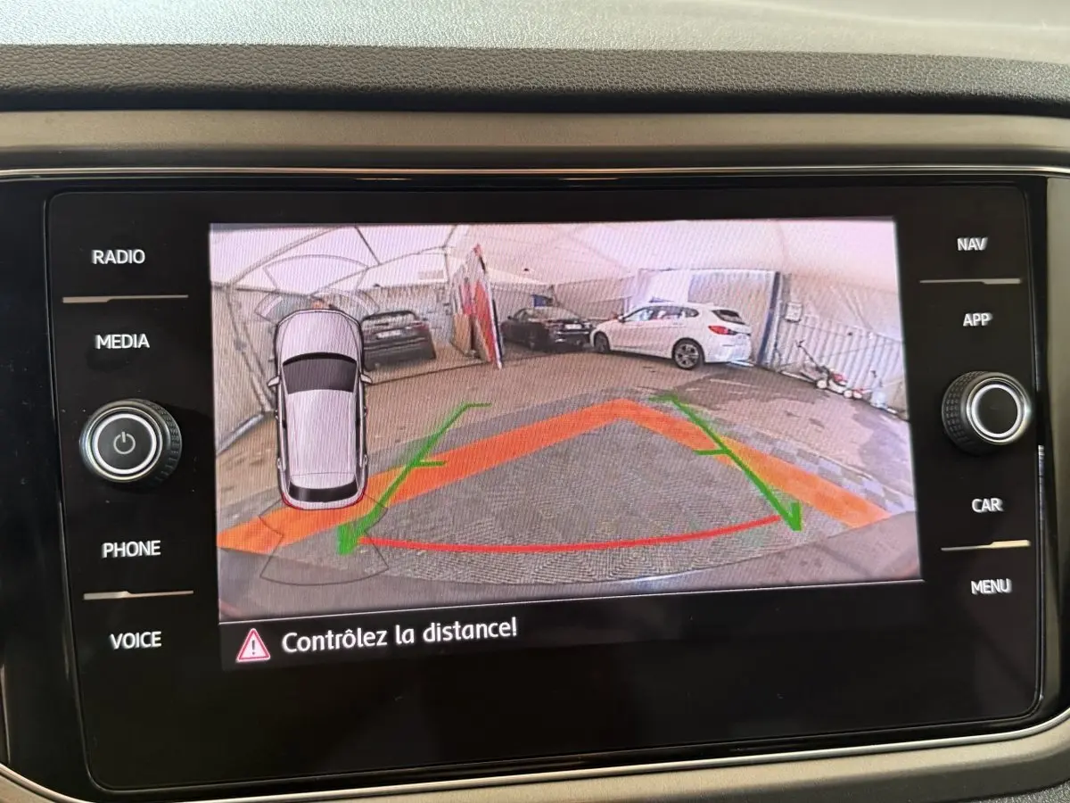 Vue de l'écran tactile du Volkswagen T-Roc noir montrant la caméra de recul avec guidage de trajectoire coloré.