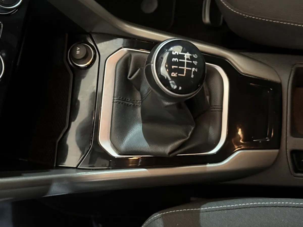 Gros plan sur le levier de vitesses manuel entouré de cuir noir dans l'habitacle du Volkswagen T-Roc 2020 noir.