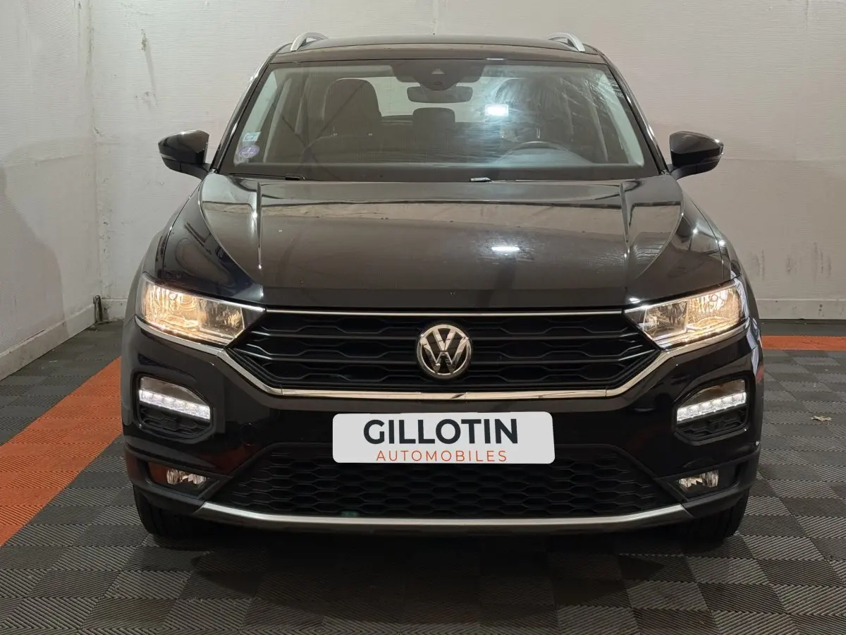 Vue frontale d'un Volkswagen T-Roc noir 2020 avec phares allumés et calandre hexagonale distinctive.