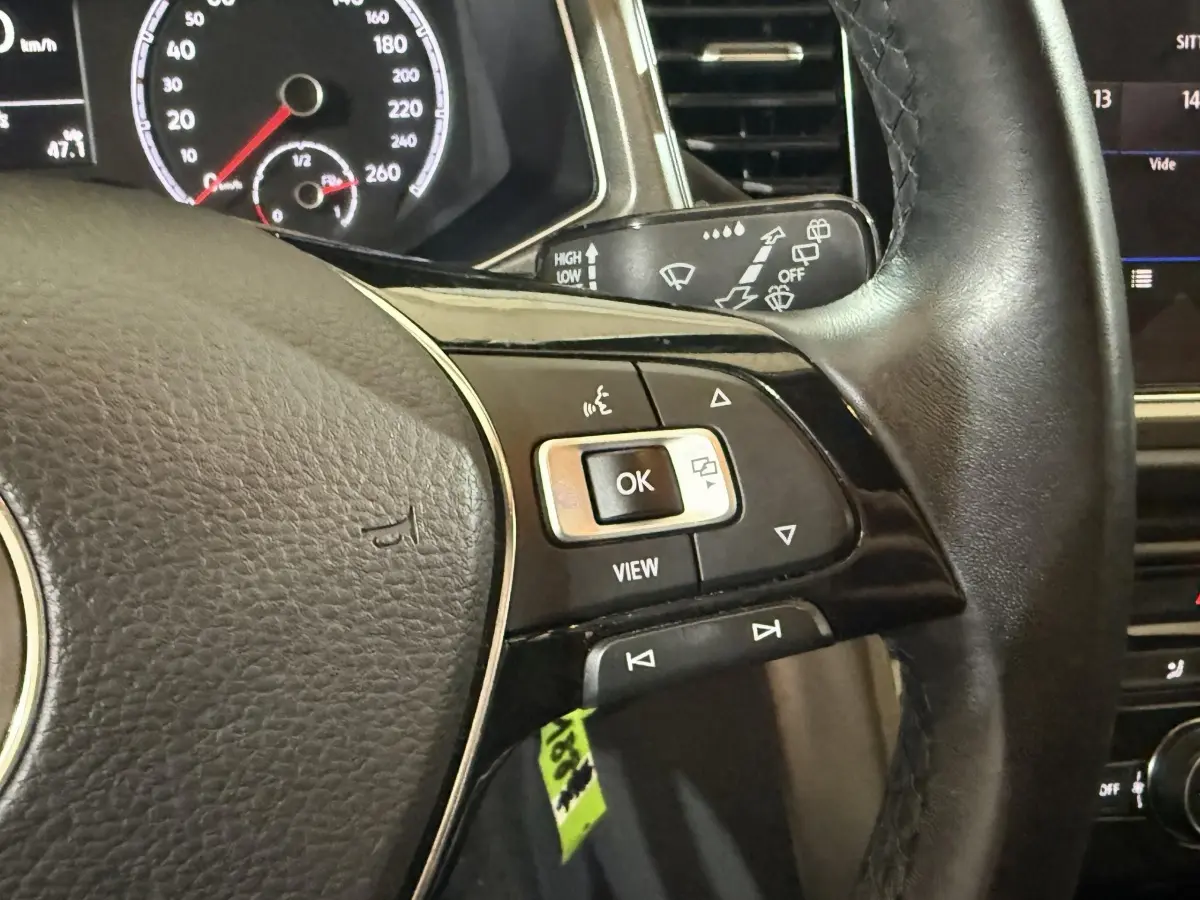 Gros plan sur le volant cuir noir du Volkswagen T-Roc 2020 avec commandes multifonctions et tableau de bord partiellement visible.