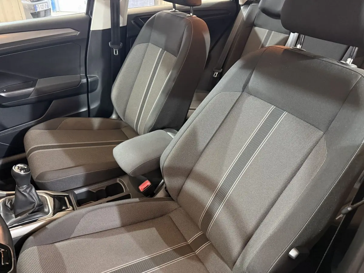 Vue intérieure côté conducteur du Volkswagen T-Roc 2020, sièges tissu gris avec bandes centrales claires et levier de vitesses manuel.