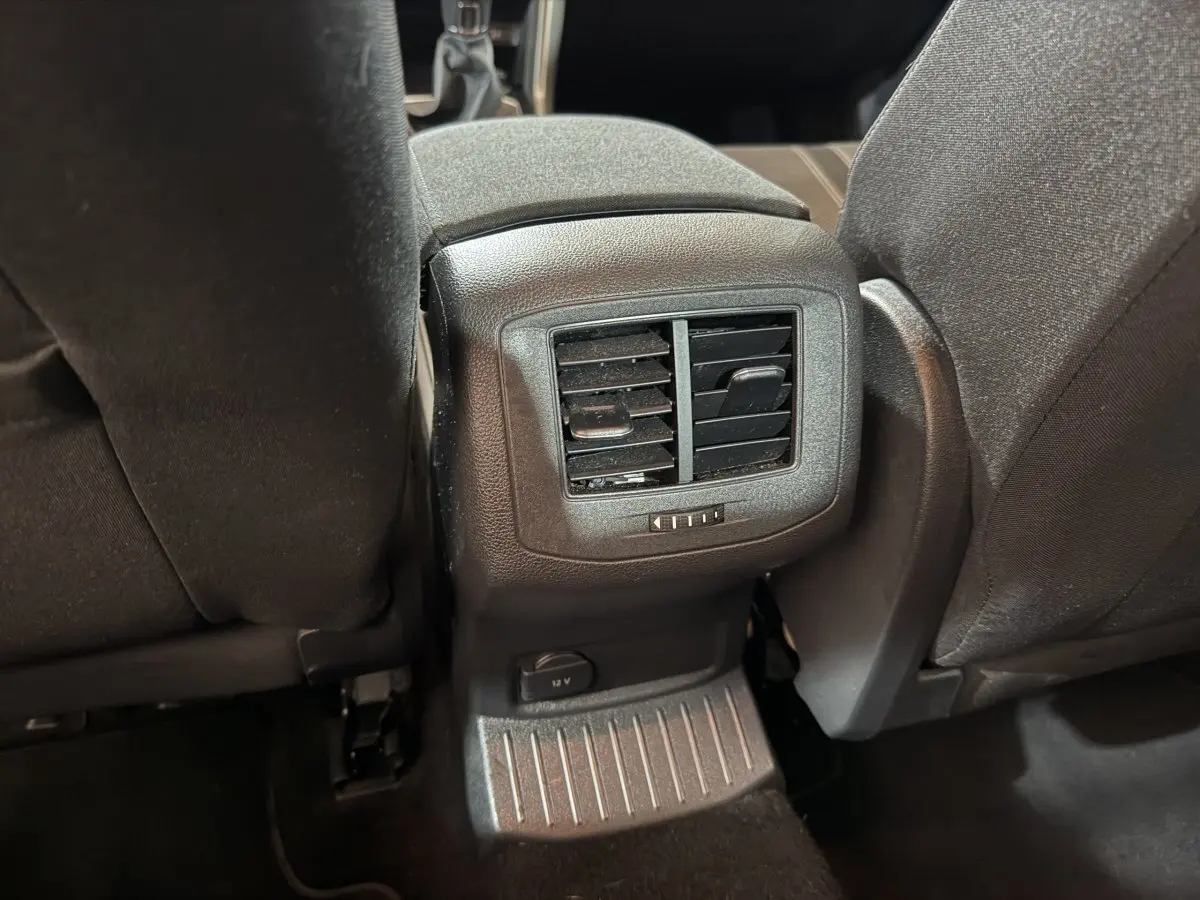 Bouche d'aération arrière et prise 12V entre les sièges noirs du Volkswagen T-Roc 2020 vue de l'intérieur arrière.