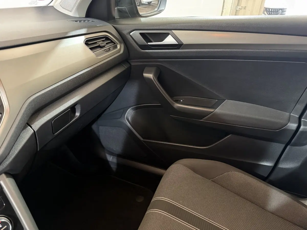 Vue intérieure côté passager du Volkswagen T-Roc 1.0 TSI 115 Lounge Business 2020 avec sellerie grise et tableau de bord noir.