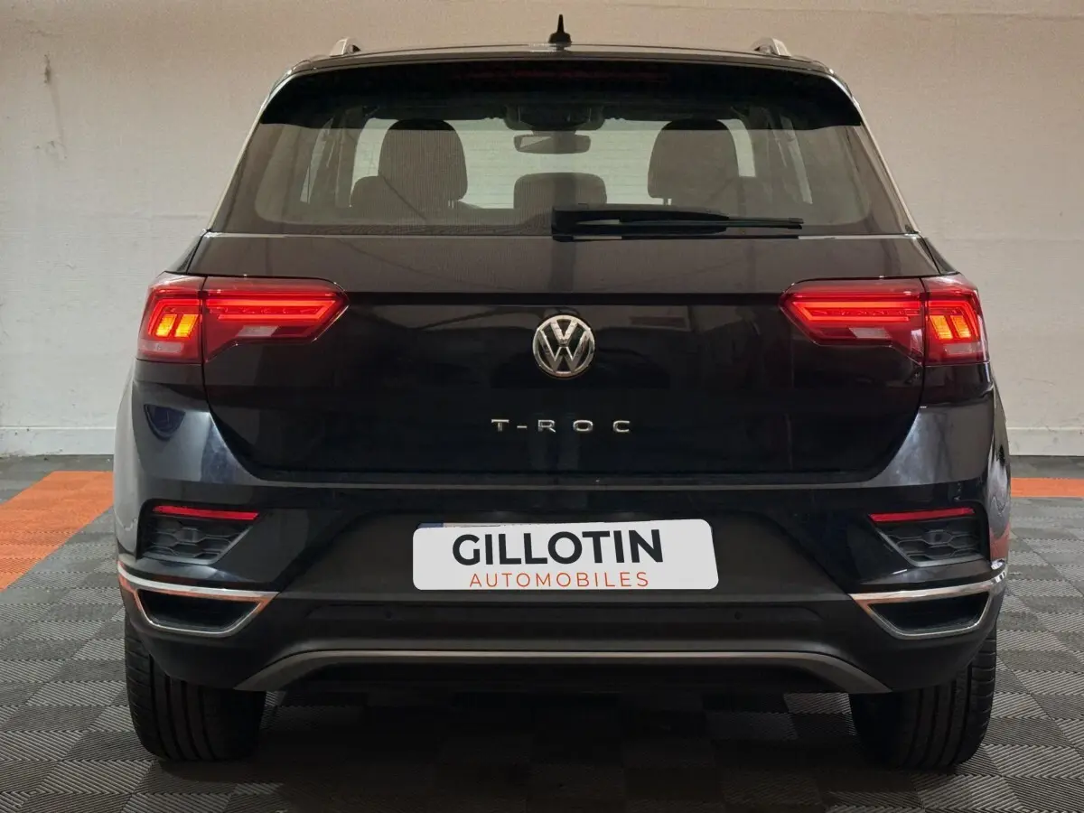 Vue arrière d'un Volkswagen T-Roc noir 2020 avec feux LED allumés et logo centré sur un sol damier.