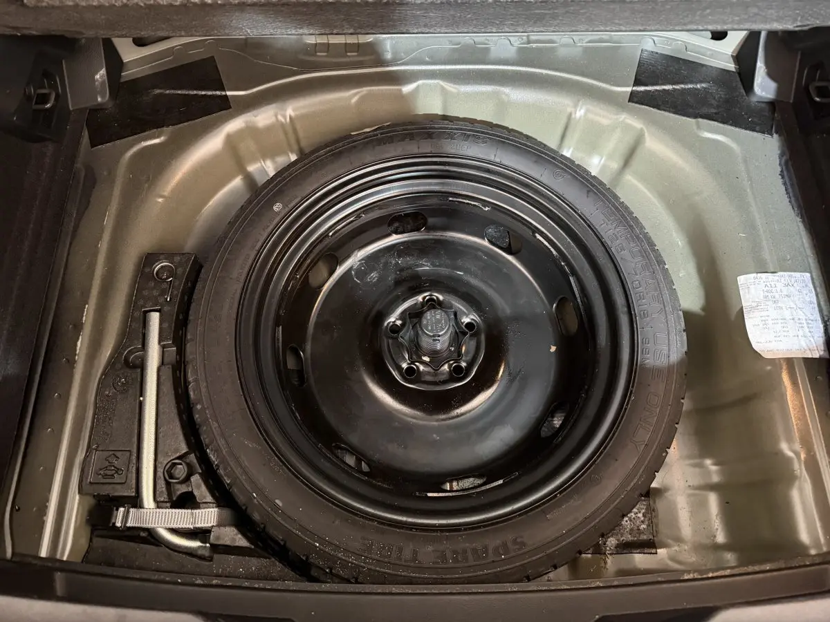 Vue plongeante sur la roue de secours noire dans le coffre d'un Volkswagen T-Roc noir 2020.