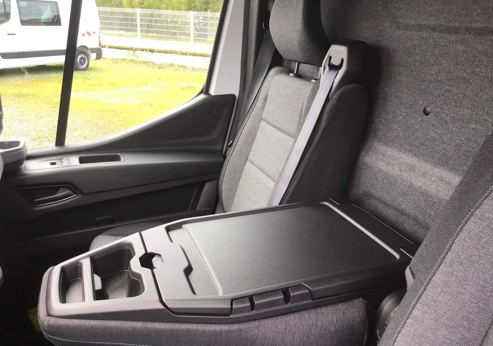 Vue intérieure côté passager du Renault Master blanc, mettant en valeur la banquette avec bureau mobile et accoudoir fermé.