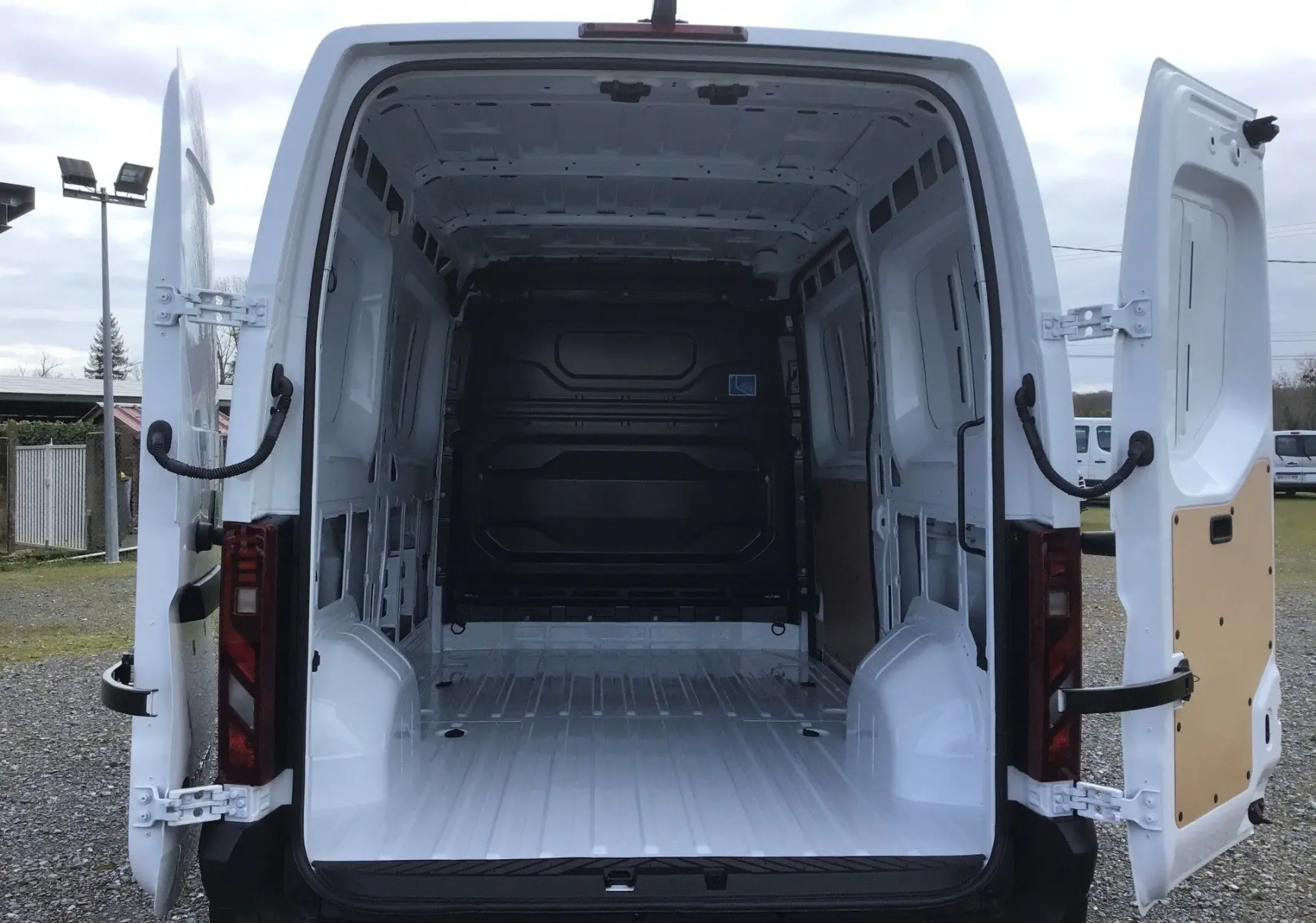 Vue arrière du Renault Master blanc avec portes ouvertes montrant l’espace de chargement vide et la cloison noire.