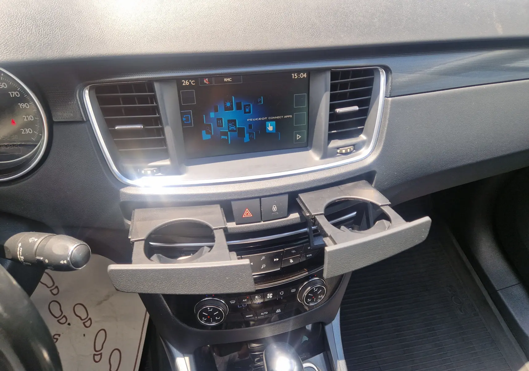 Vue intérieure du tableau de bord de la Peugeot 508 SW gris Shark, avec écran tactile et porte-gobelets déployés.