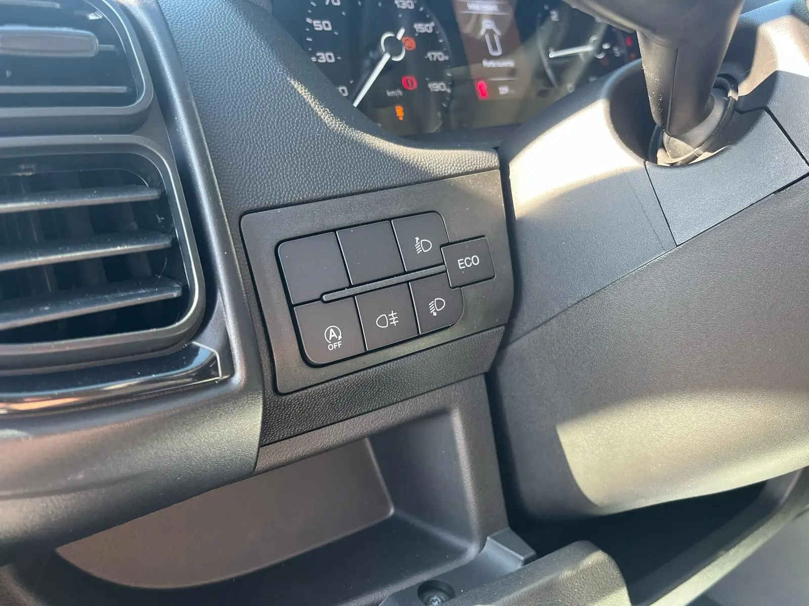 Gros plan sur les commandes d'éclairage et mode ECO à gauche du tableau de bord du Fiat Ducato Fourgon blanc 2023.