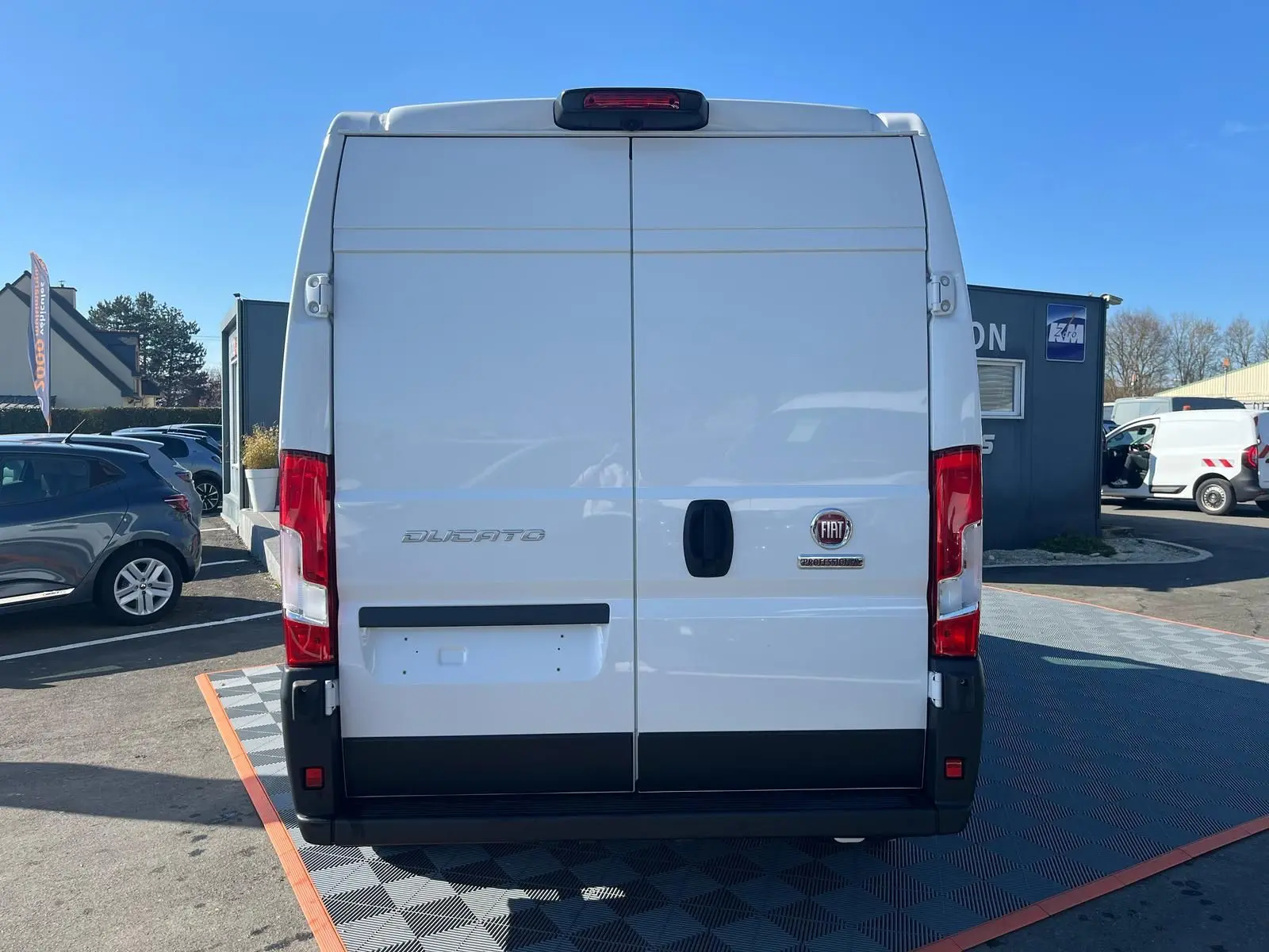 Vue arrière du fourgon blanc FIAT Ducato 2023 avec portes battantes et feux rouges verticaux.