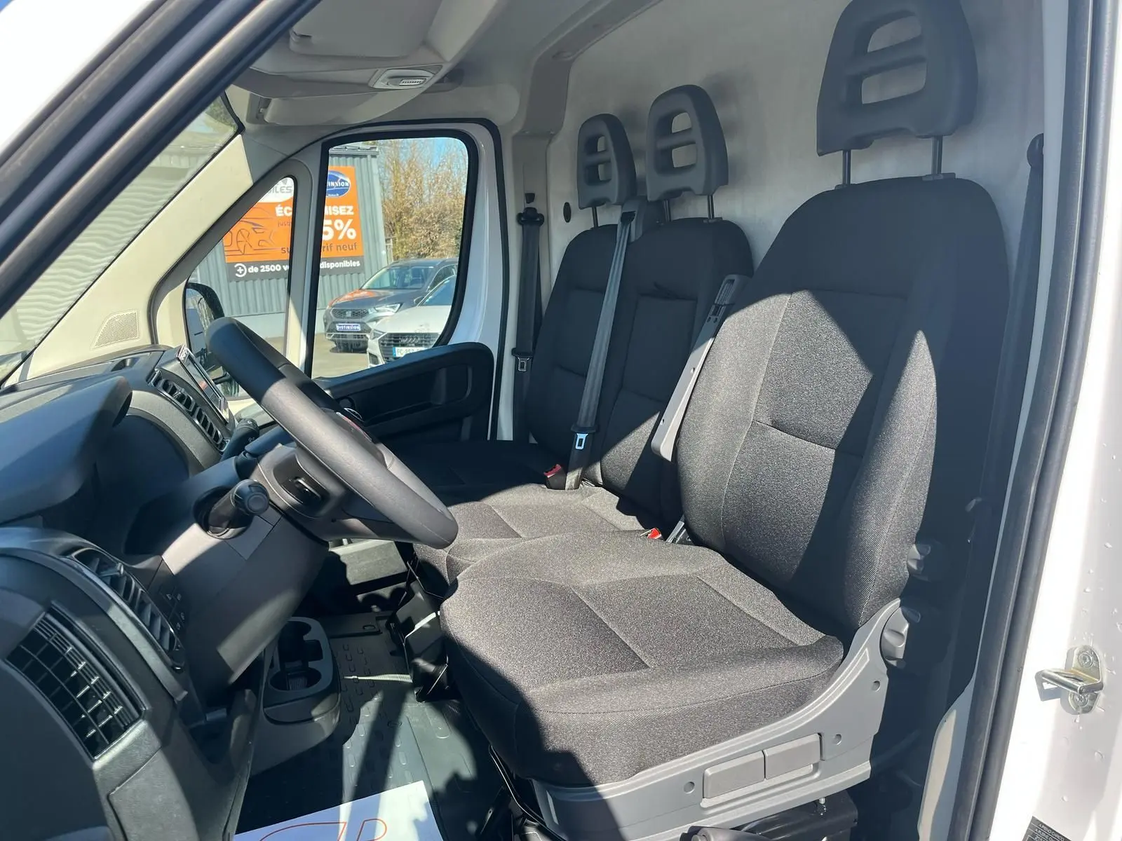 Intérieur du FIAT Ducato Fourgon blanc 2023, vue côté conducteur montrant les trois sièges noirs et le tableau de bord.