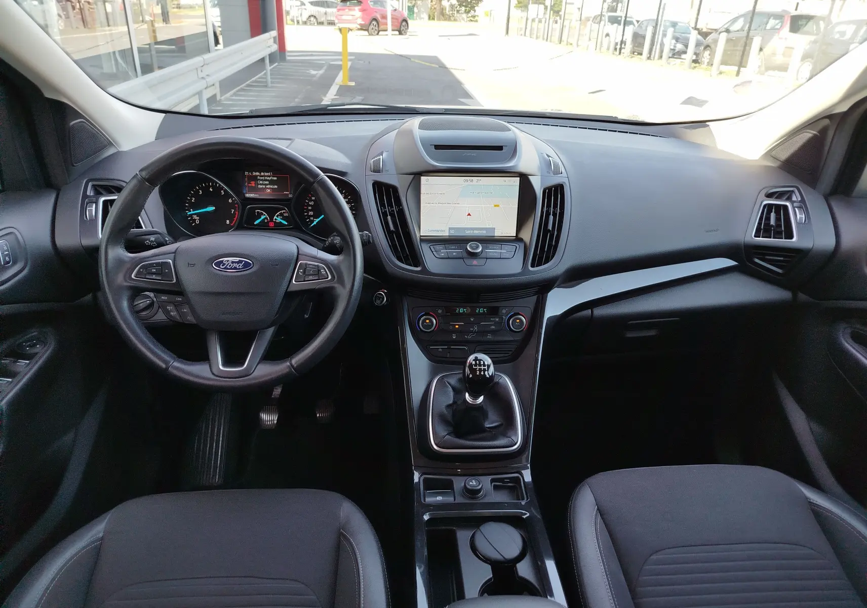 Vue intérieure du tableau de bord et volant noir du Ford Kuga 2019 avec boîte manuelle et écran tactile central.