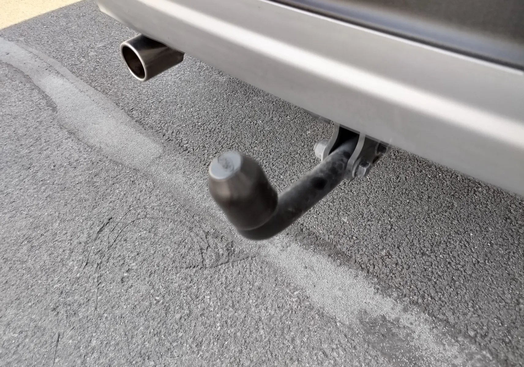 Gros plan sur l'attelage d'une Ford Kuga gris clair, visible sous le pare-chocs arrière côté droit.