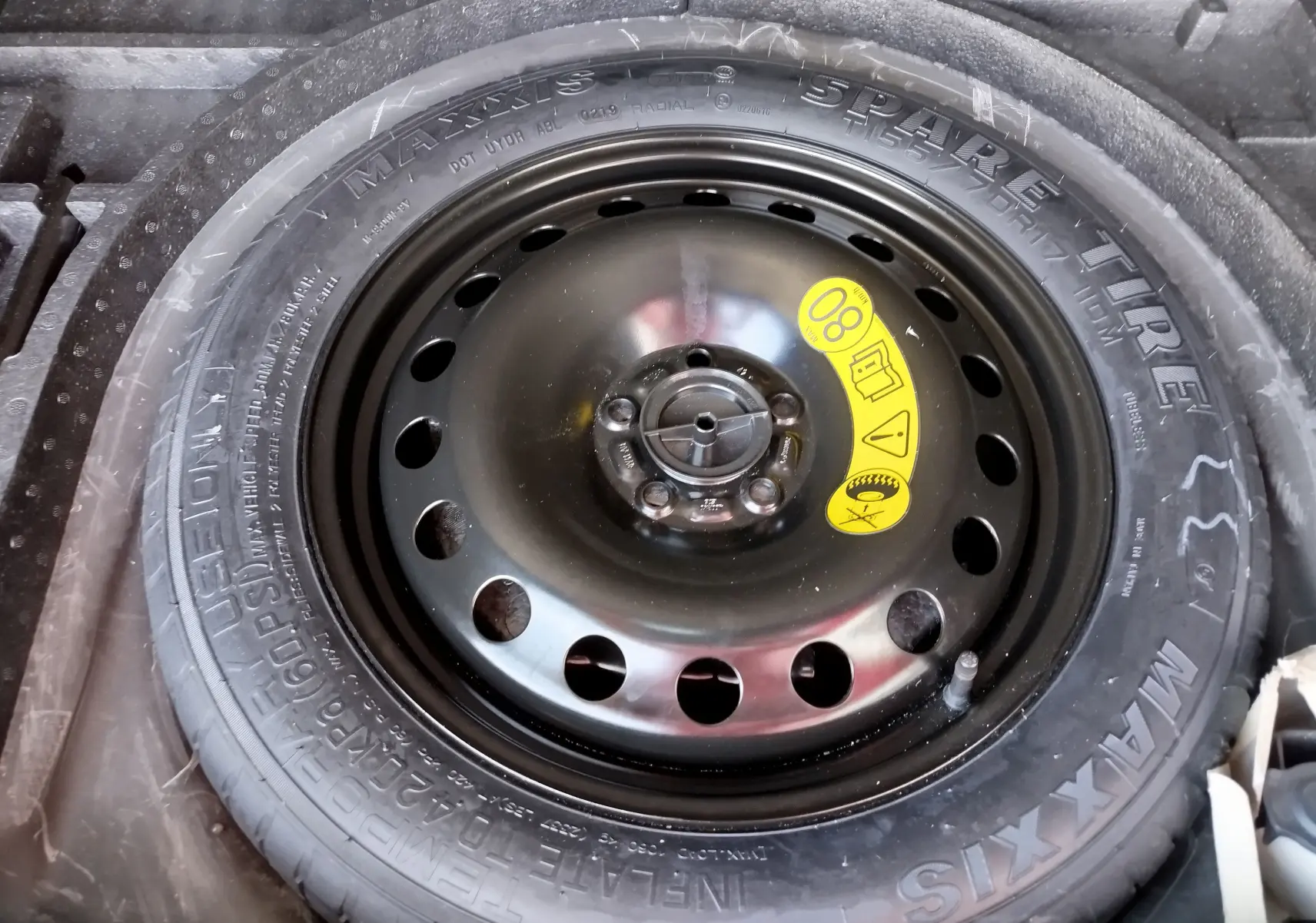 Gros plan sur la roue de secours noire du Ford Kuga gris clair, avec étiquette jaune indiquant la vitesse maximale 80 km/h.