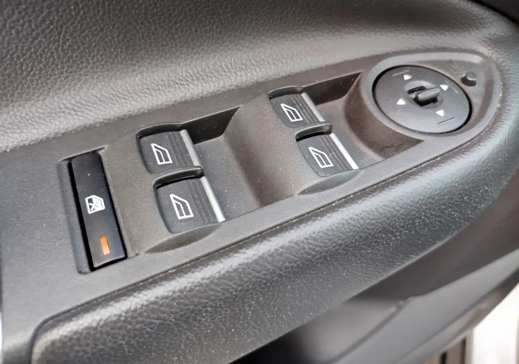 Gros plan sur les commandes de lève-vitres et réglage des rétroviseurs côté conducteur du Ford Kuga gris clair 2019.