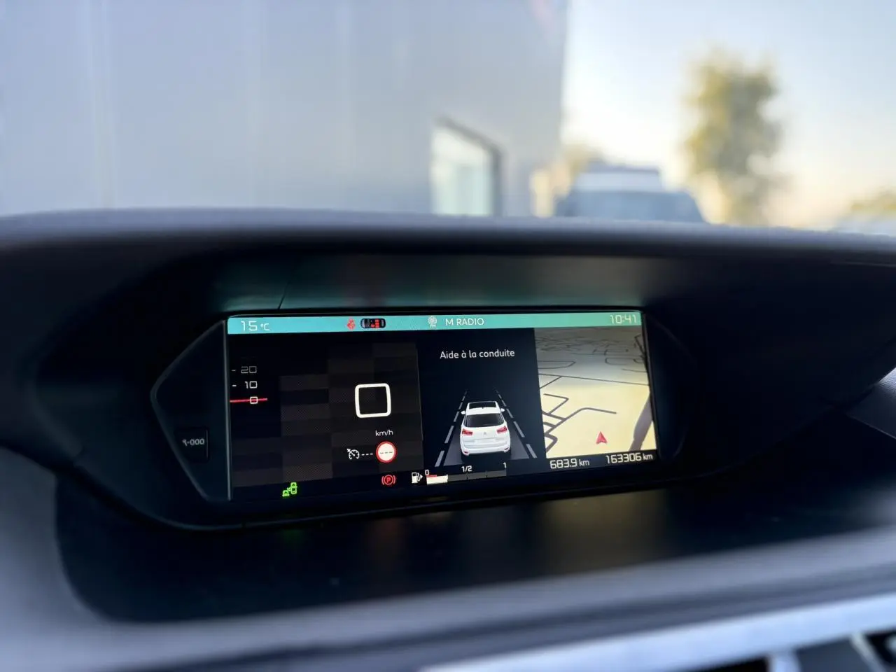 Écran panoramique du tableau de bord montrant l'aide à la conduite et la navigation du Citroën C4 Picasso gris Platinium.