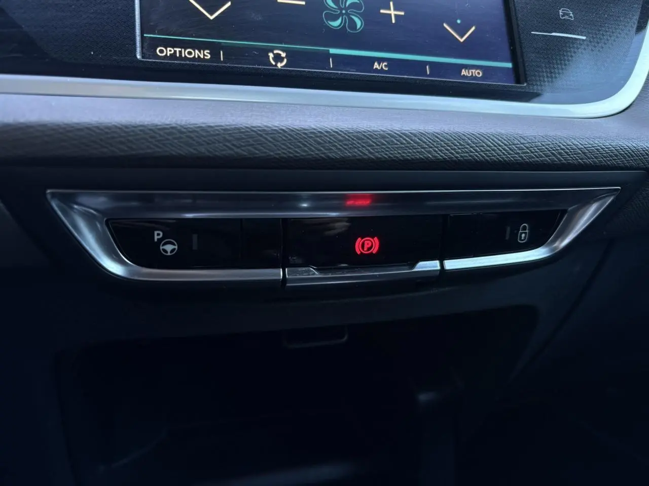 Gros plan sur la console centrale du Citroën C4 Picasso 2017 montrant le frein de stationnement électrique actif.