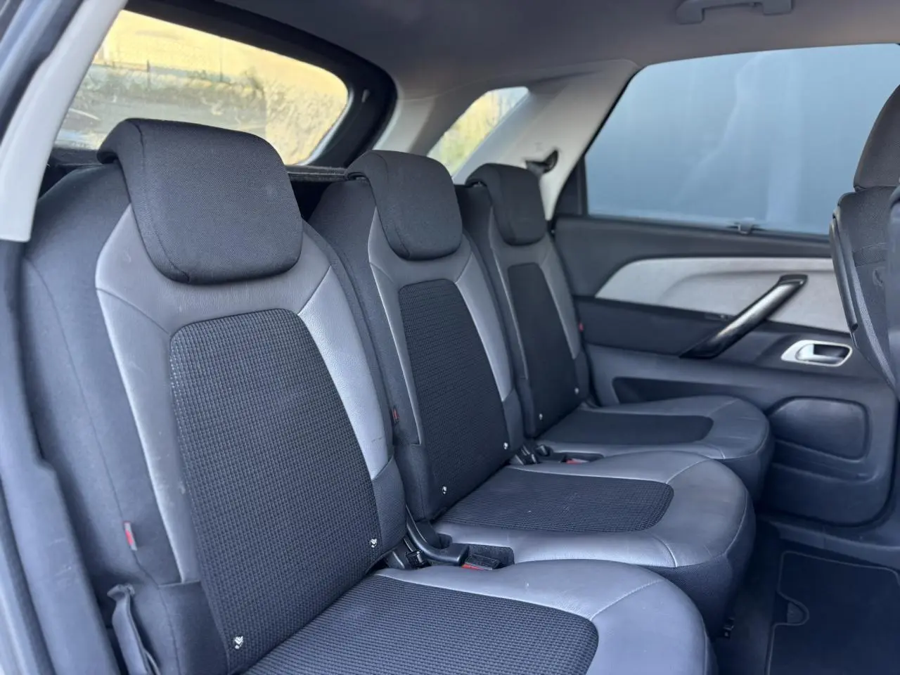 Vue latérale des sièges arrière en tissu noir et cuir gris du Citroën C4 Picasso 2017, avec stores latéraux arrière visibles.