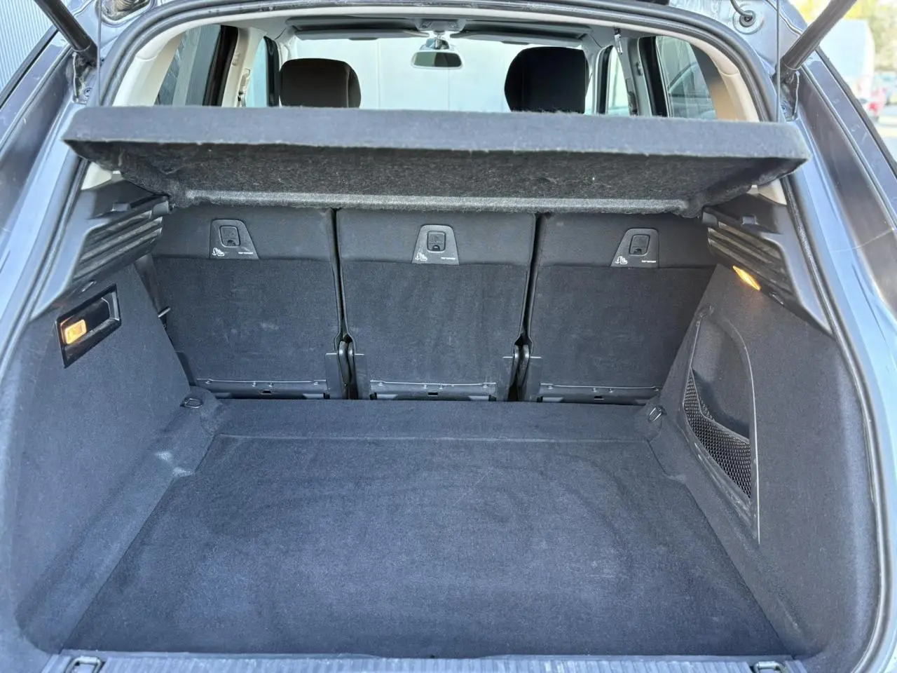 Coffre spacieux ouvert de Citroën C4 Picasso gris Platinium, montrant la tablette cache-bagages et les sièges arrière rabattables.