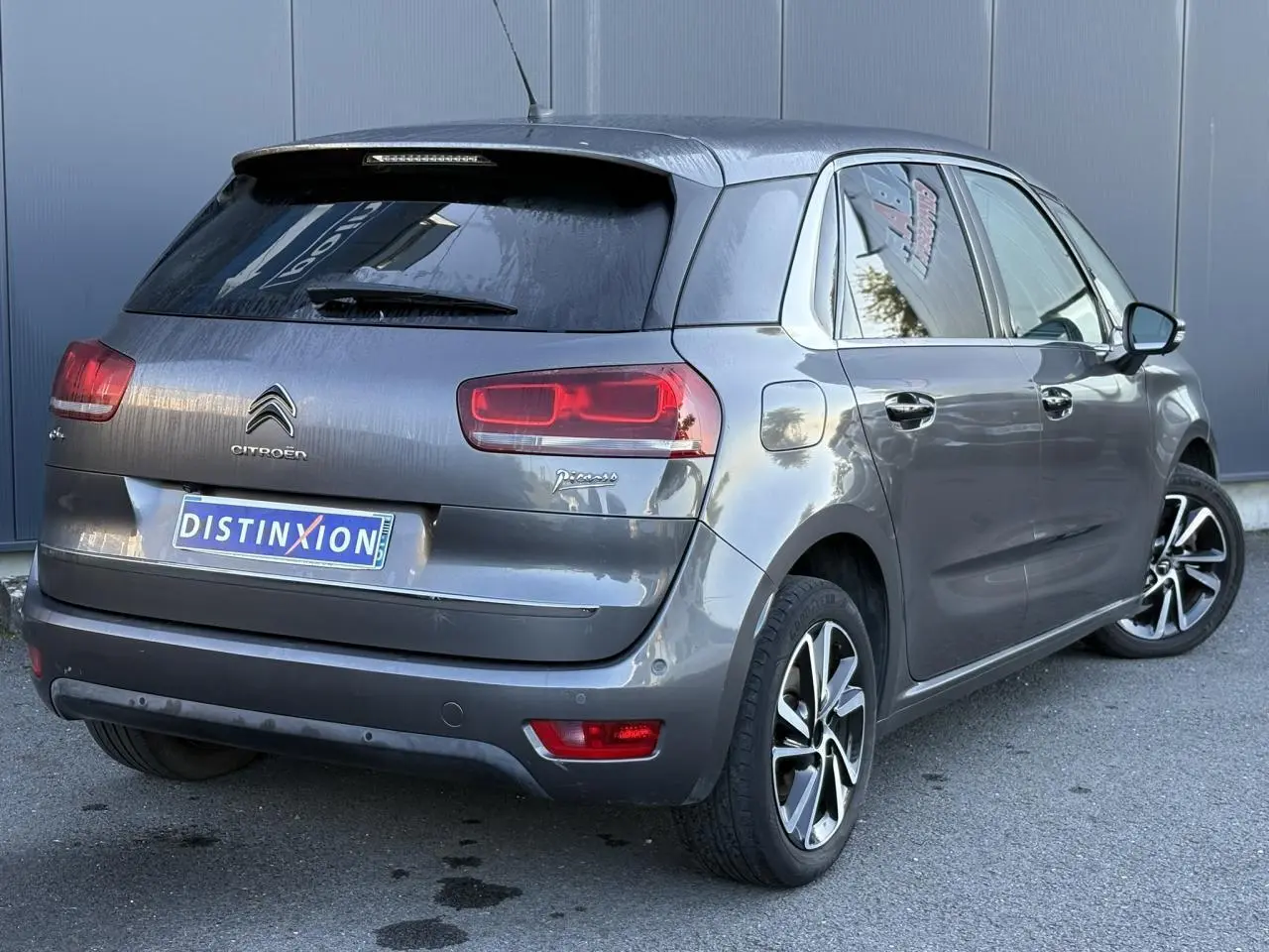 Vue 3/4 arrière droite d'une Citroën C4 Picasso gris Platinium avec feux arrière LED et jantes alliage bi-ton.