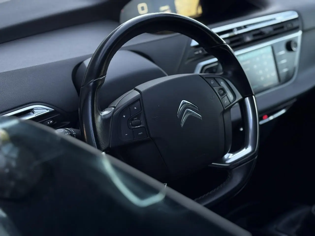 Volant en cuir noir avec commandes intégrées dans l'habitacle d'une Citroën C4 Picasso 2017, tableau de bord flou en arrière-plan.