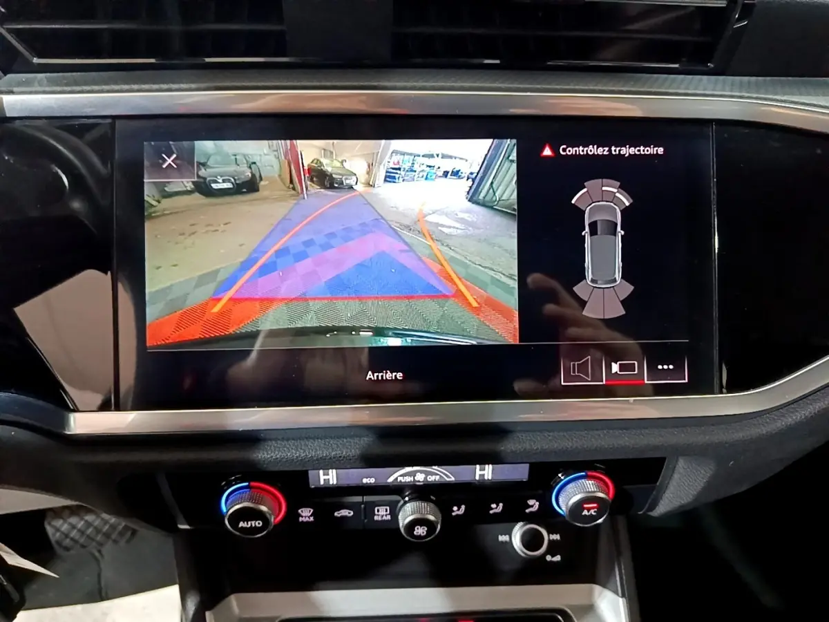 Écran tactile central de l'Audi Q3 noir 2020 montrant la caméra de recul et l'aide au stationnement arrière.