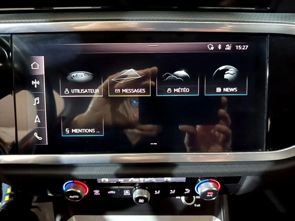 Écran tactile central et commandes de climatisation du tableau de bord de l'Audi Q3 noir, vue rapprochée intérieure.