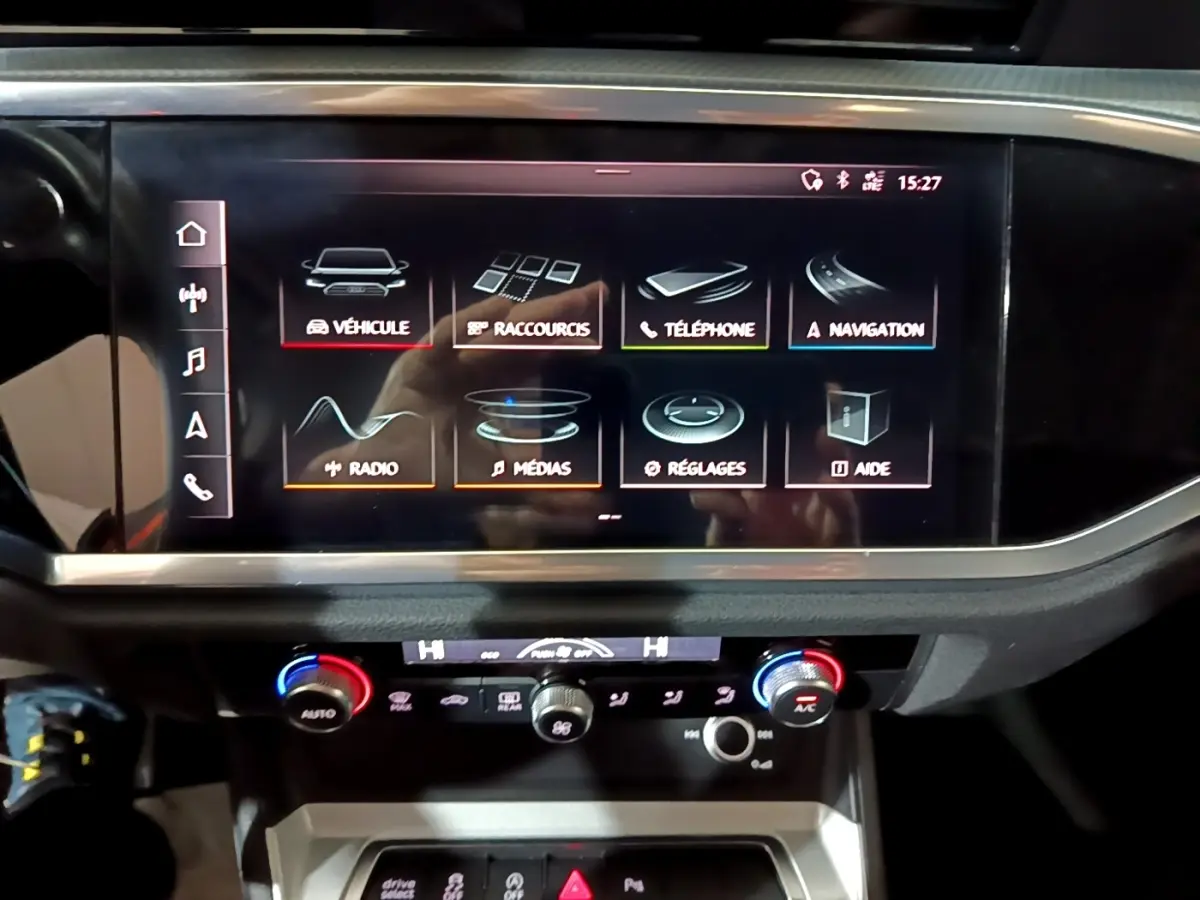 Écran tactile central et commandes climatisation du tableau de bord de l'Audi Q3 noir vue de face.
