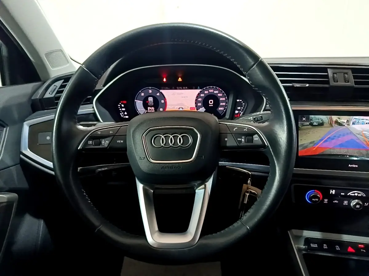 Vue intérieure centrée sur le volant cuir noir et le tableau de bord digital de l'Audi Q3 35 TDI Business Line 2020.