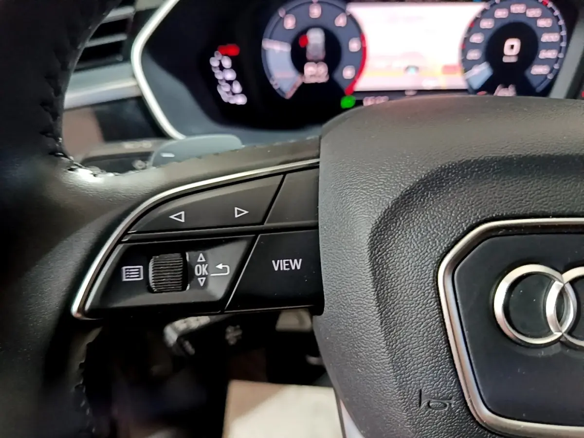 Gros plan sur le volant noir d'Audi Q3 35 TDI 150 S tronic Business Line avec commandes multifonctions et tableau de bord numérique.