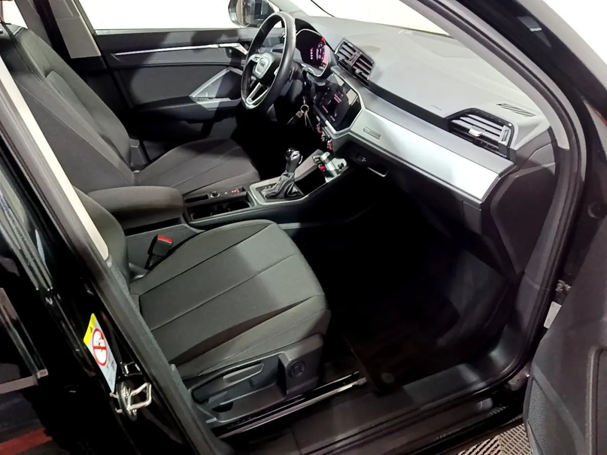 Intérieur côté conducteur de l'Audi Q3 noir 2020, avec tableau de bord moderne et volant multifonctions cuir.