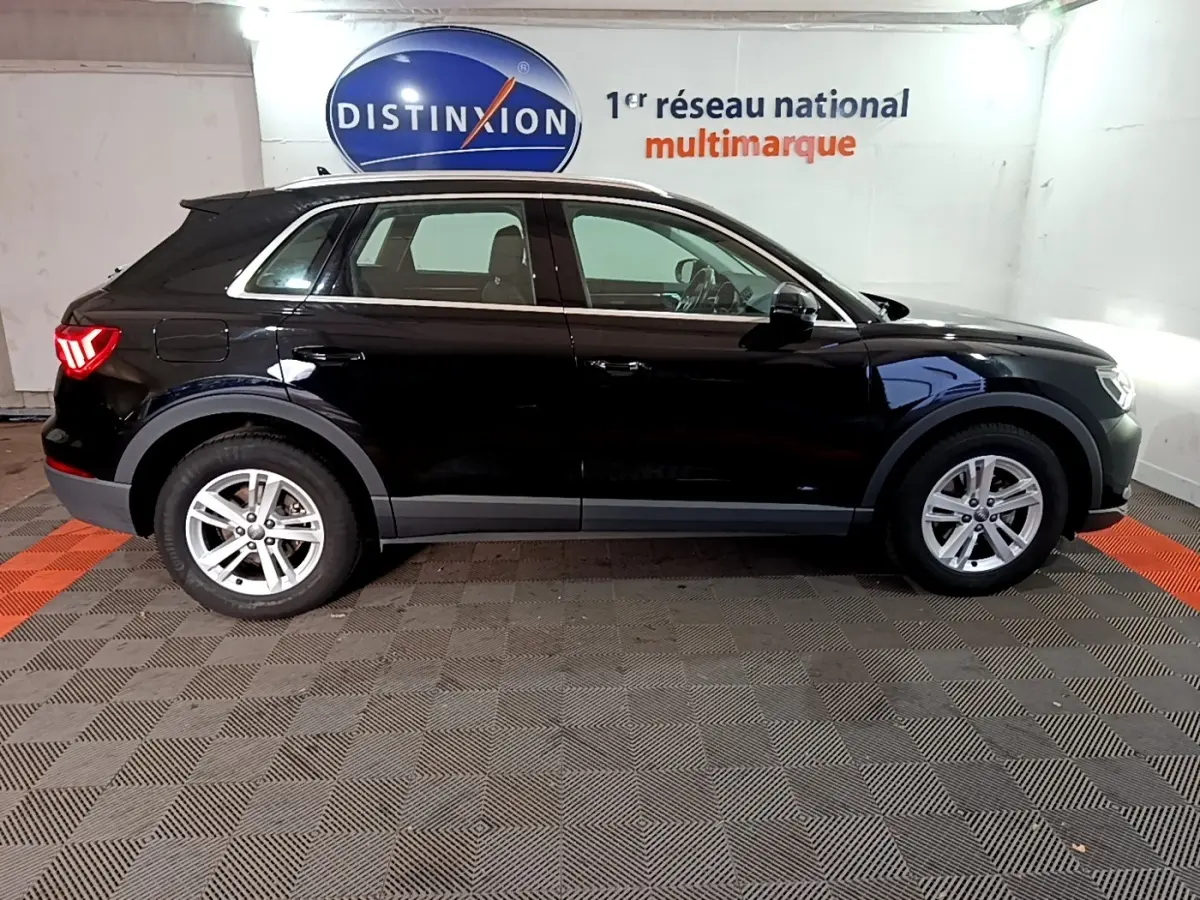 Profil côté gauche d'un Audi Q3 noir 2020 garé en intérieur avec jantes argentées et feux arrière allumés.