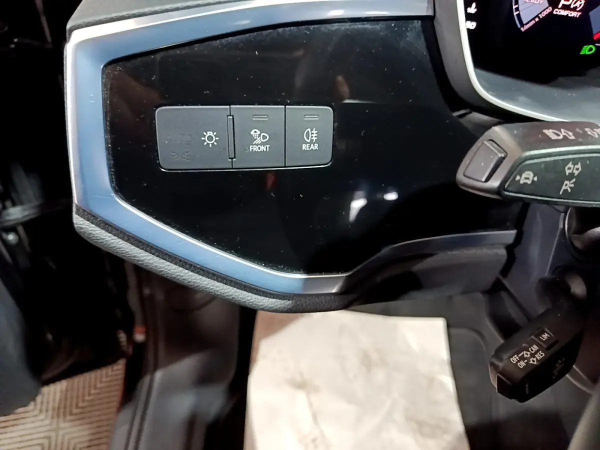 Détail du tableau de bord noir de l'Audi Q3 35 TDI 2020 montrant les commandes d'éclairage avant et arrière.