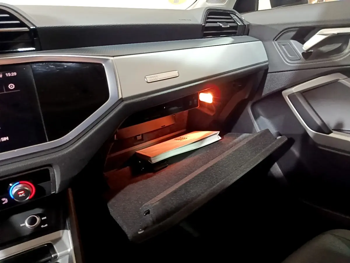 Vue intérieure côté passager de l'Audi Q3 35 TDI 150 S tronic Business Line 2020, boîte à gants ouverte avec manuel visible.