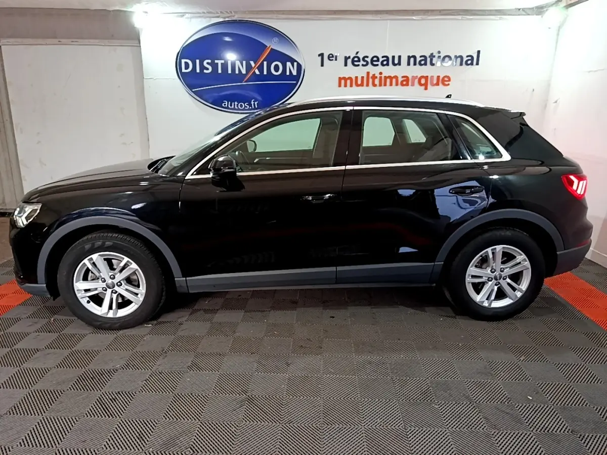 Audi Q3 noir vue de profil côté gauche, stationné en intérieur avec logo Distinxion en arrière-plan.