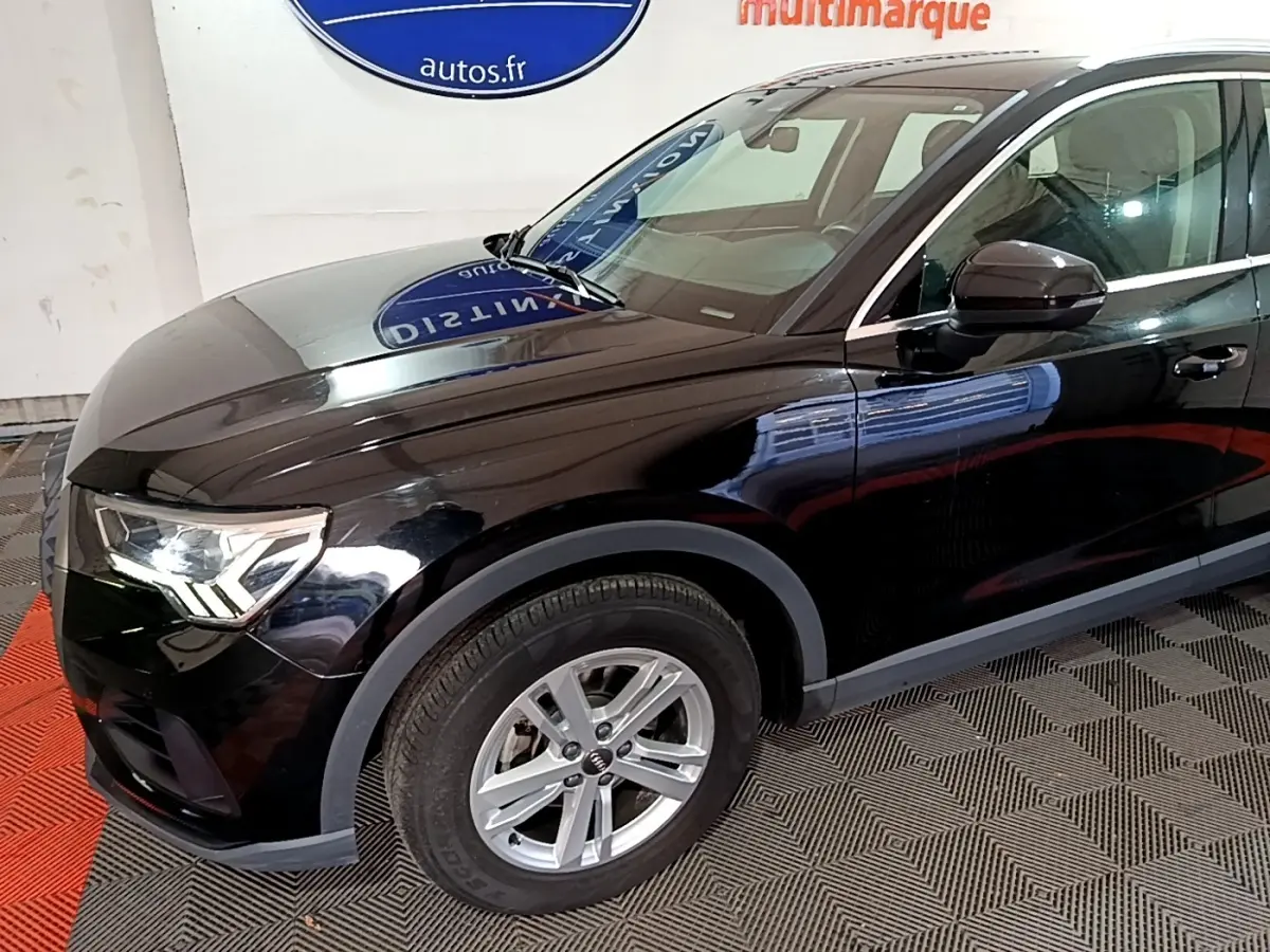 Vue 3/4 avant gauche d'un Audi Q3 noir avec jantes alliage et rétroviseur noir brillant.